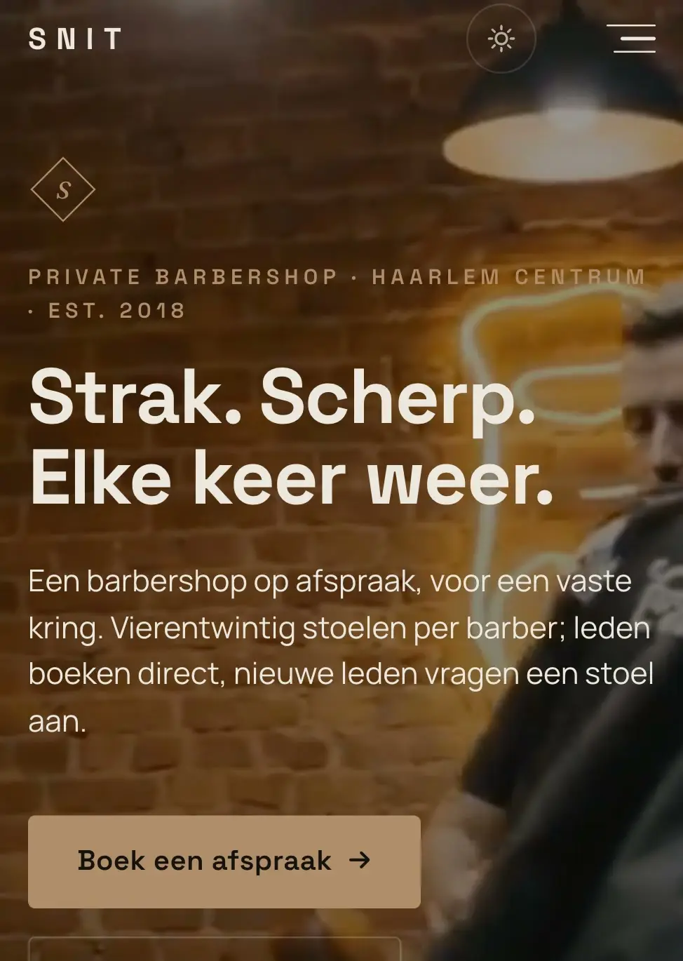 De homepage van voorbeeldzaak SNIT op een telefoon: donkere barbershop met warm lamplicht
